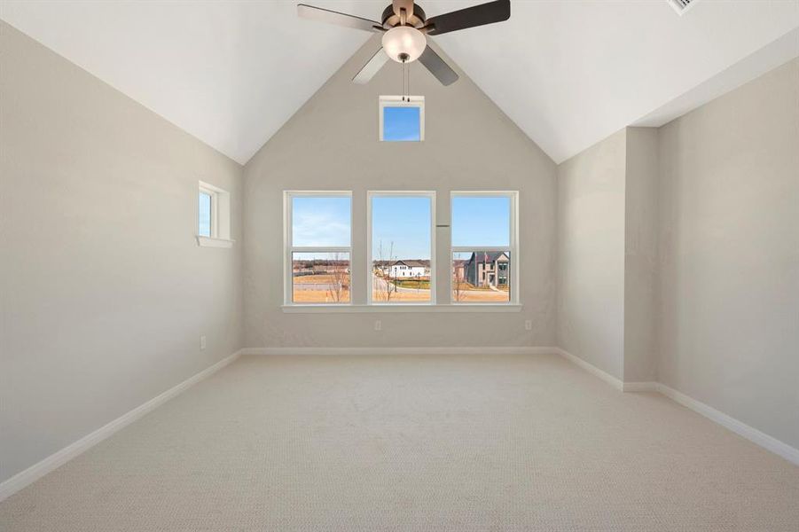 Spare room featuring light carpet, ceiling fan, and a high ceiling