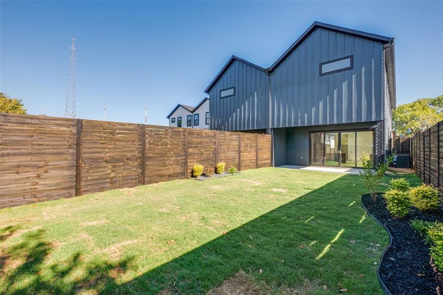 Back of property featuring board and batten siding, a fenced backyard, and a patio