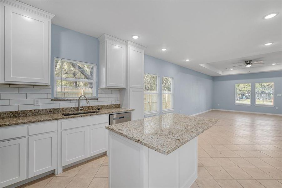 Kitchen with white cabinets, ceiling fan, sink, and tasteful backsplash