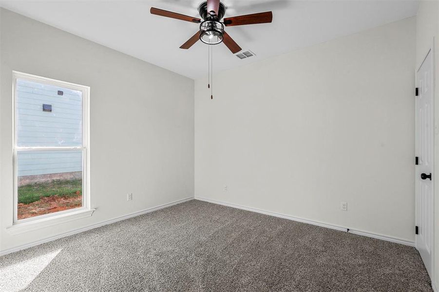 Spare room featuring carpet and ceiling fan