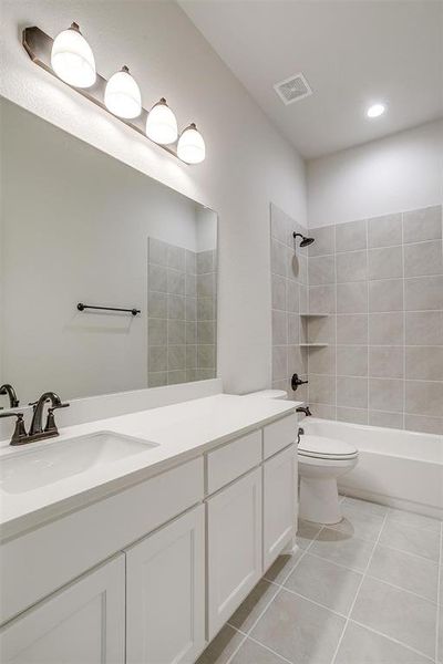 Full bathroom featuring tile patterned floors, vanity, toilet, and tiled shower / bath combo