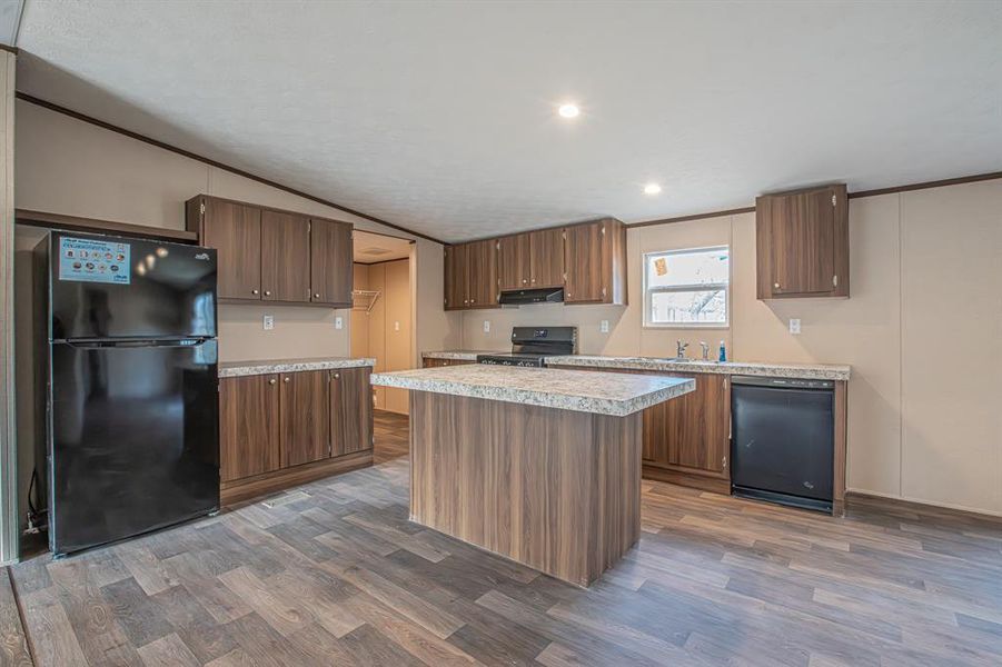 Kitchen with a center island, dark wood-type flooring, vaulted ceiling, black appliances, and exhaust hood Kitchen with a center island, dark wood-type flooring, vaulted ceiling, black appliances, and exhaust hood