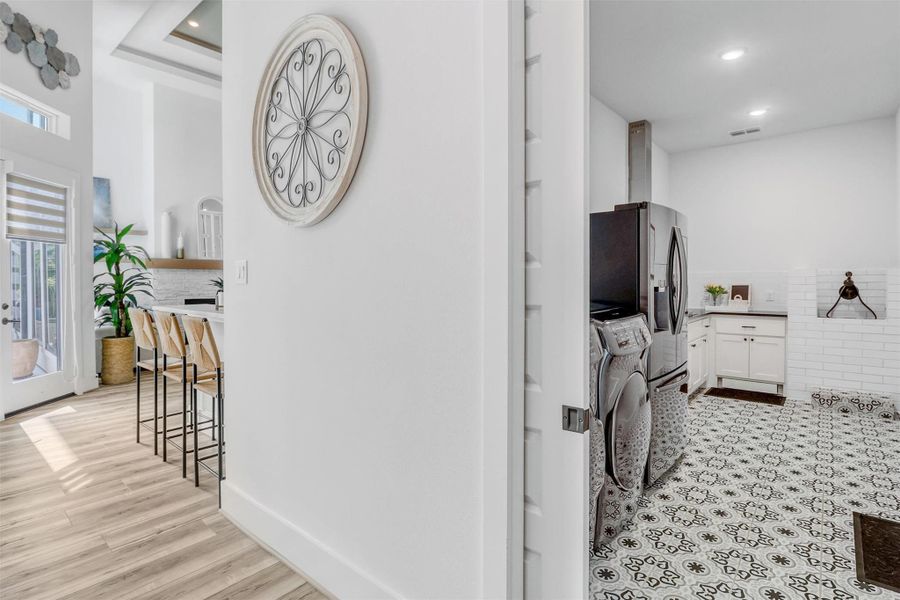 Behind the kitchen, find a multi-functional utility room. Pocket doors open up to beautiful custom tile flooring, washer and dryer, space for a refrigerator, a dog wash station, and a second kitchen!
