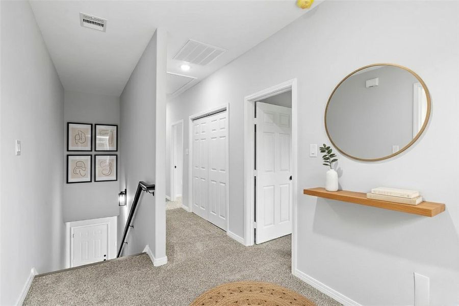 Bright and inviting hallway with neutral walls, carpeted floor, and a modern design. **Photo has been staged.**