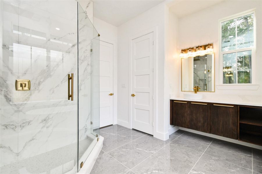 Luxury continues with a floating dark-wood vanity, vessel sink, and designer lighting fixtures.