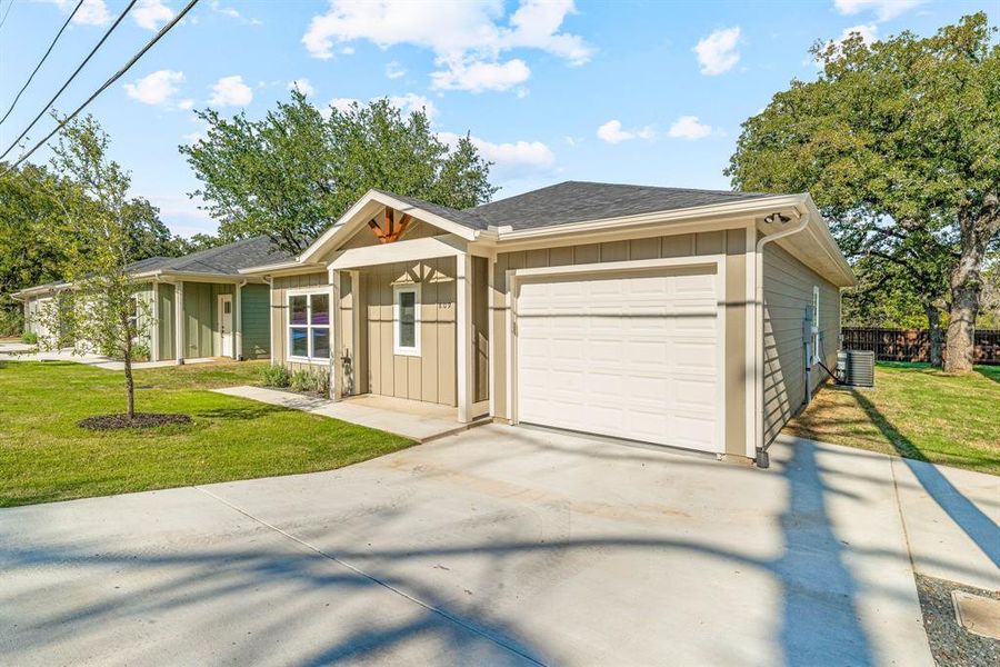 View of front of property with board and batten siding, a front yard, roof with shingles, concrete driveway, and a garage View of front of property with board and batten siding, a front yard, roof with shingles, concrete driveway, and a garage