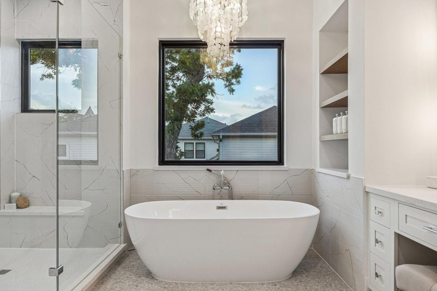71 Inch Soaking Tub with a Wall Mounted Tub Filler, Ribbed Marble Tile Tub Surround, GlossyBronze Tiered Chandelier with Natural White Shell, White Oak Floating Shelves with a Natural Stain. 71 Inch Soaking Tub with a Wall Mounted Tub Filler, Ribbed Marble Tile Tub Surround, GlossyBronze Tiered Chandelier with Natural White Shell, White Oak Floating Shelves with a Natural Stain.
