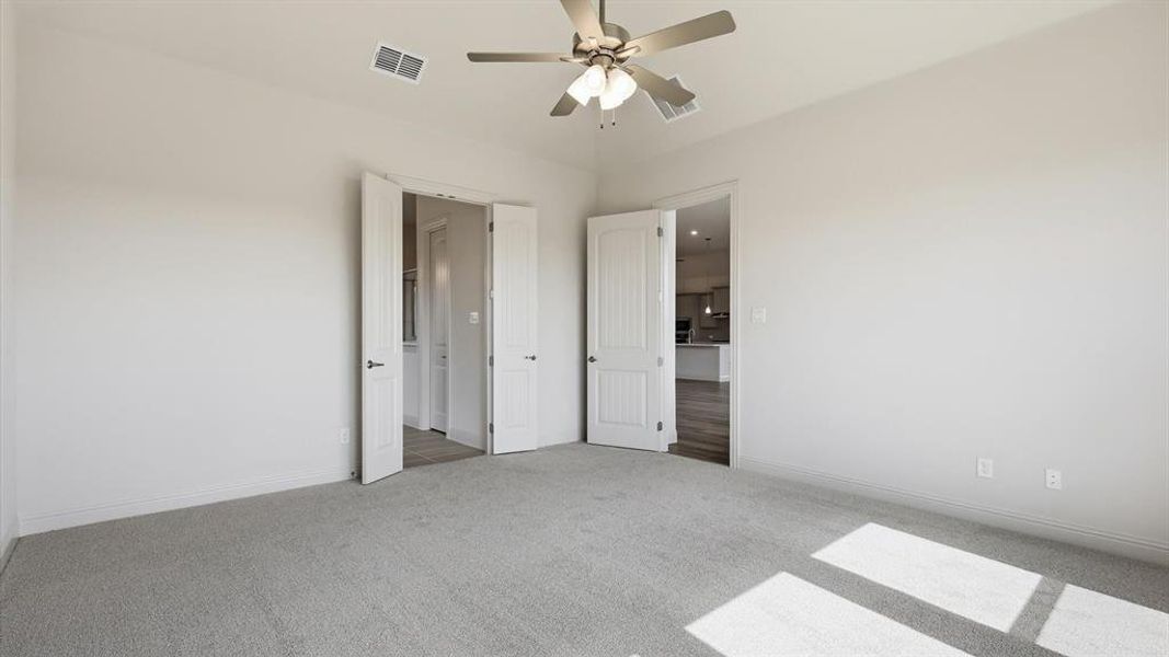 Carpeted room featuring a ceiling fan with integrated lighting, white walls, and white trim