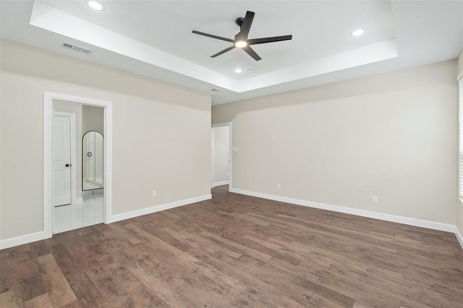 Spare room with a raised ceiling, dark wood finished floors, recessed lighting, and ceiling fan
