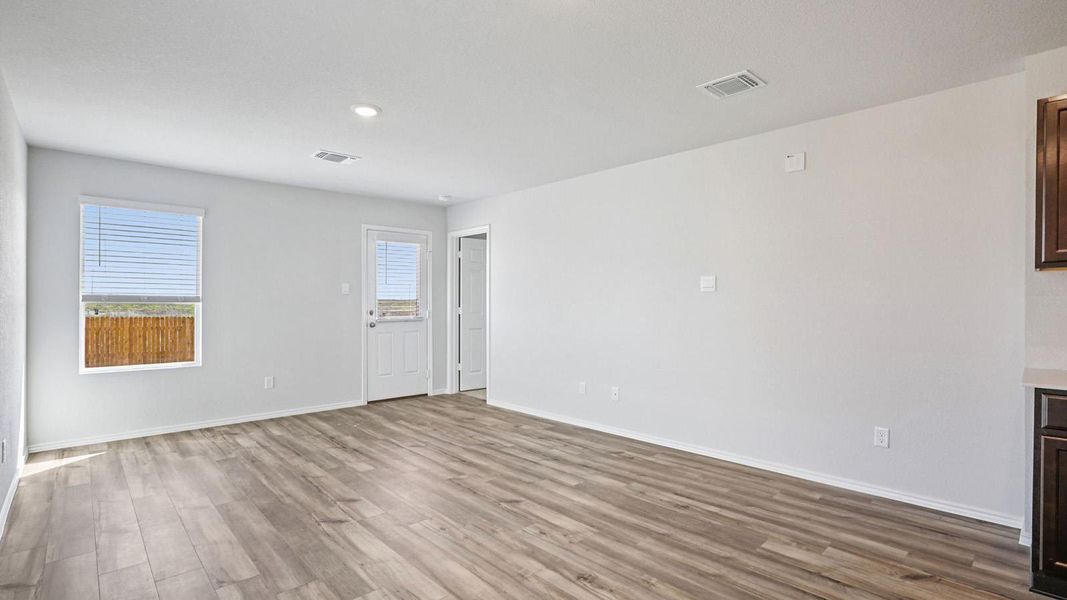 Natural light fills this versatile open living area, featuring durable plank flooring and convenient rear access. Natural light fills this versatile open living area, featuring durable plank flooring and convenient rear access.
