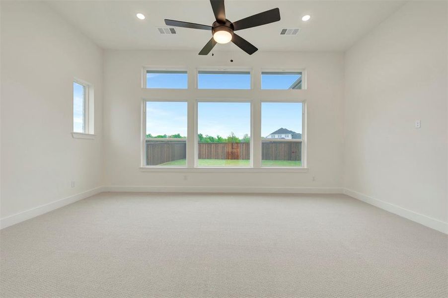 Owners Retreat with light carpet, a ceiling fan, and recessed lighting