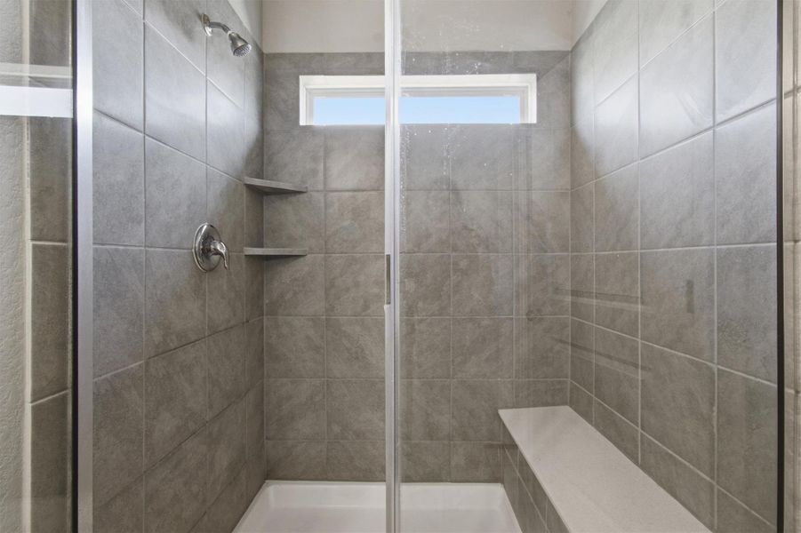 A well-appointed, naturally illuminated shower with a built-in bench and glass enclosure.