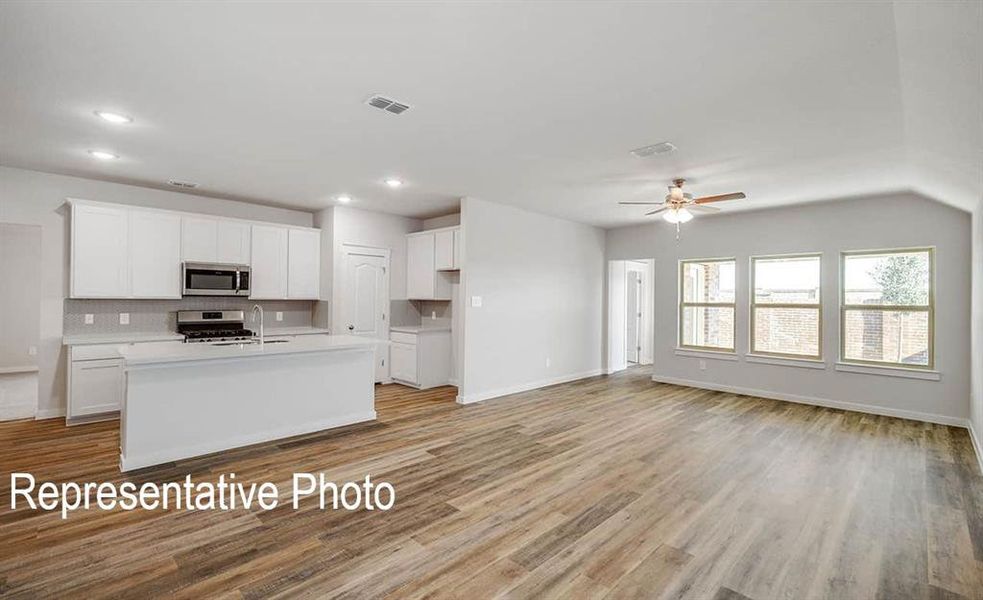 Kitchen with a kitchen island with sink, stainless steel appliances, light hardwood / wood-style floors, and white cabinetry