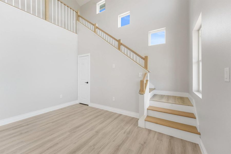 This bright, spacious room features high ceilings, modern light flooring, and a stylish staircase with wooden accents. Large windows provide ample natural light, enhancing the open feel. This bright, spacious room features high ceilings, modern light flooring, and a stylish staircase with wooden accents. Large windows provide ample natural light, enhancing the open feel.