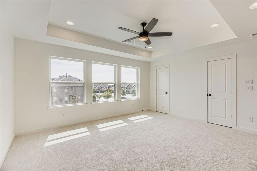 Unfurnished bedroom featuring a tray ceiling, light carpet, recessed lighting, and a ceiling fan