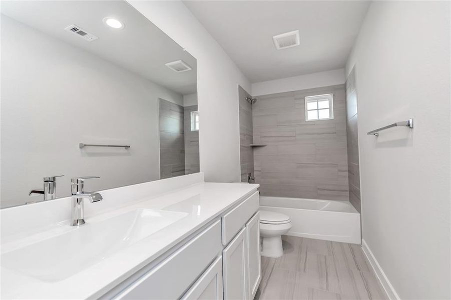 Indulge in refined charm in the secondary bathroom, where the tile flooring harmonizes with a bath/shower combo surrounded by tasteful tile. Light wood cabinets, coupled with a gorgeous countertop, elevate the space, cultivating a truly welcoming atmosphere.