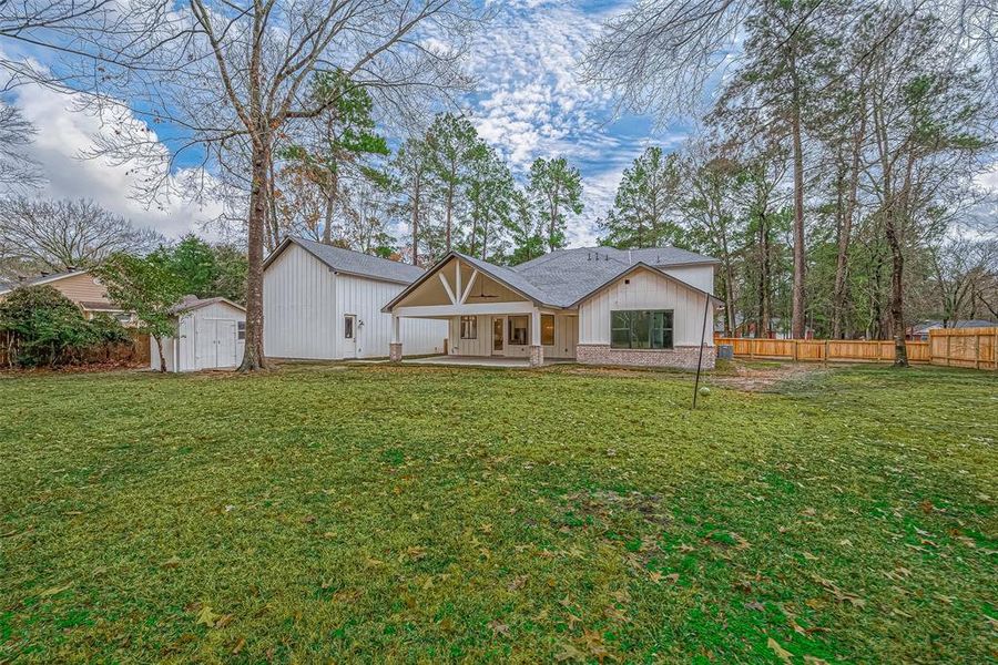 spacious backyard the house has a white exterior with large windows and a covered patio.