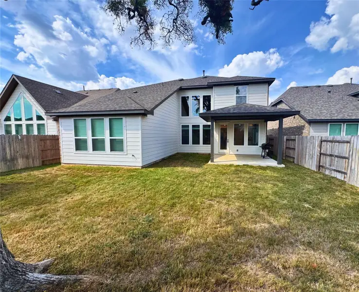 Back of property with a fenced backyard, a patio area, and a shingled roof