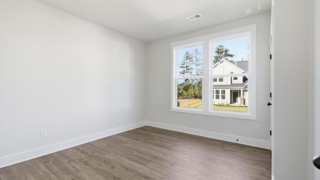 Thoughtfully designed secondary bedrooms featuring hardwood flooring and tasteful detail