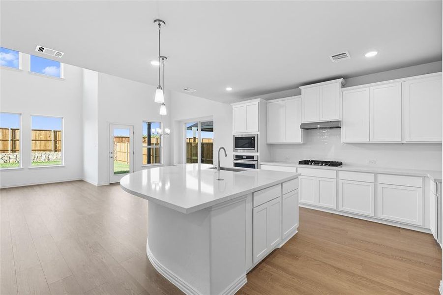 Kitchen with a center island with sink, white cabinets, hanging light fixtures, healthy amount of natural light, and recessed lighting Kitchen with a center island with sink, white cabinets, hanging light fixtures, healthy amount of natural light, and recessed lighting