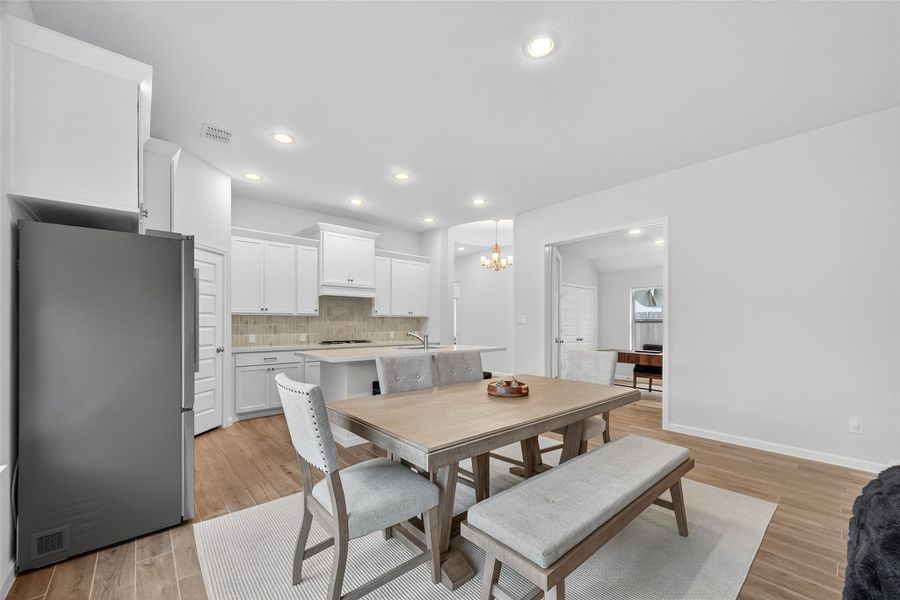 This spacious, modern kitchen and dining area features sleek white cabinetry, stainless steel appliances, and warm wood flooring, creating a welcoming atmosphere ideal for family gatherings. This spacious, modern kitchen and dining area features sleek white cabinetry, stainless steel appliances, and warm wood flooring, creating a welcoming atmosphere ideal for family gatherings.