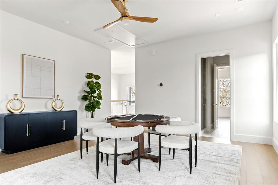 Light wood-finish flooring with a light-toned area rug, recessed ceiling lighting, and a modern ceiling fan