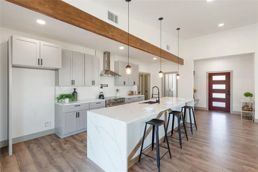 Kitchen with electric range, visible vents, a sink, wood finished floors, and wall chimney exhaust hood