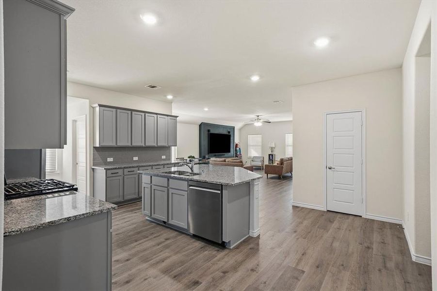 Kitchen with open floor plan, light stone counters, gray cabinets, and recessed lighting Kitchen with open floor plan, light stone counters, gray cabinets, and recessed lighting
