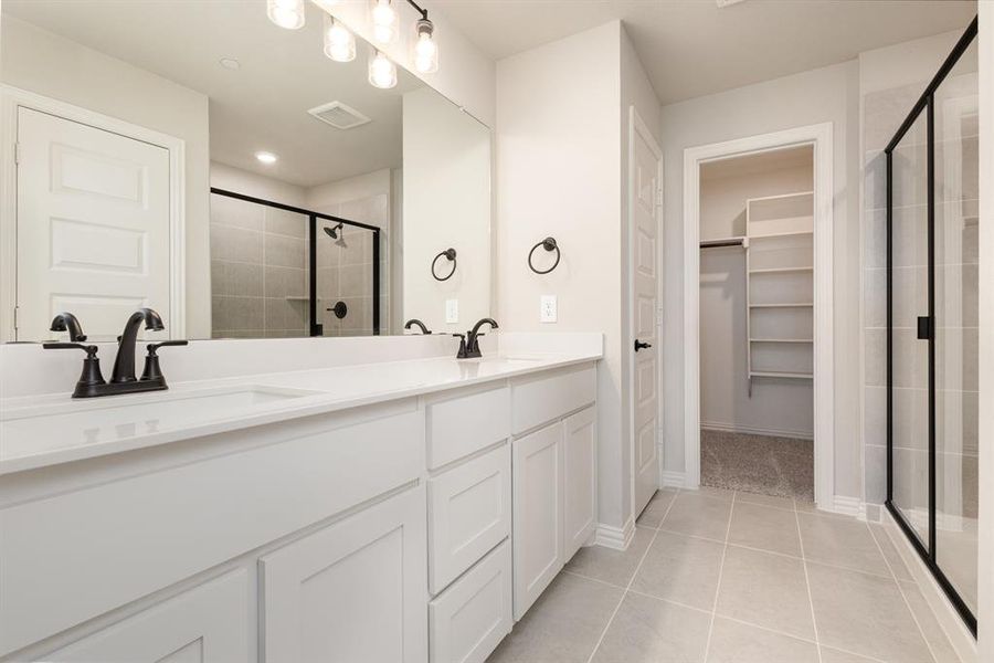 Bathroom with vanity, a shower with shower door, and tile patterned floors