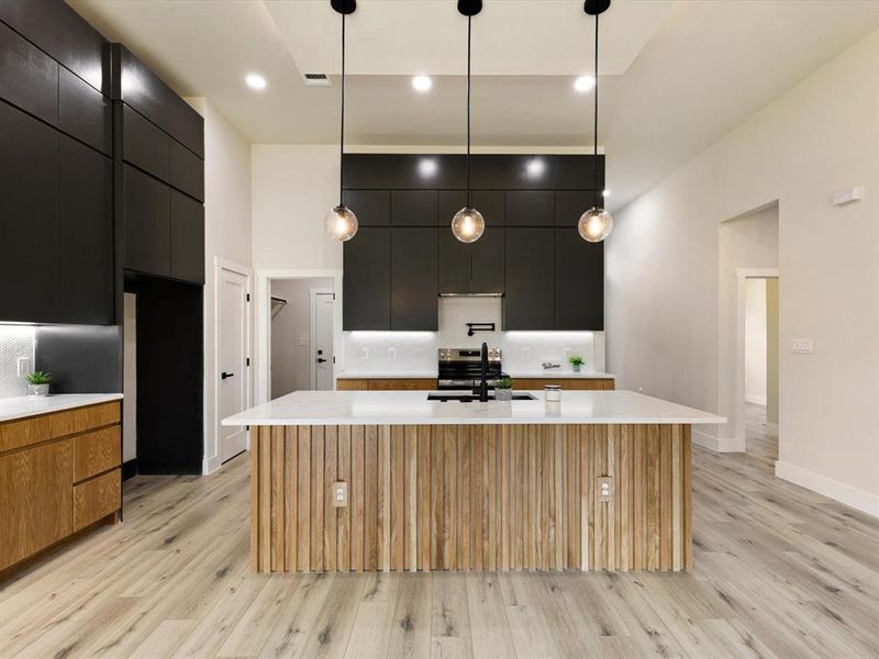 Kitchen with dark cabinets, pendant lighting, modern cabinets, light wood-type flooring, and recessed lighting