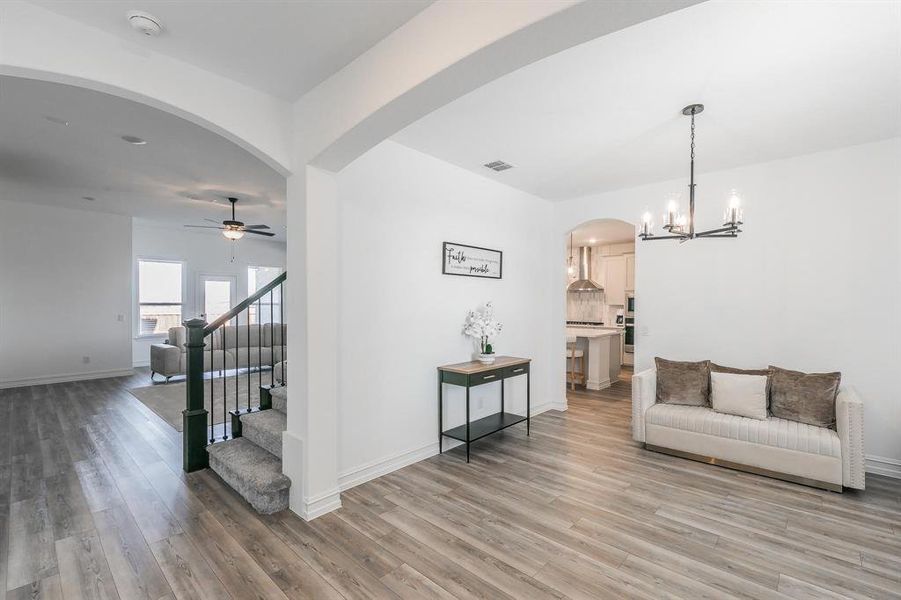 Living room featuring wood-type flooring and ceiling fan with notable chandelier