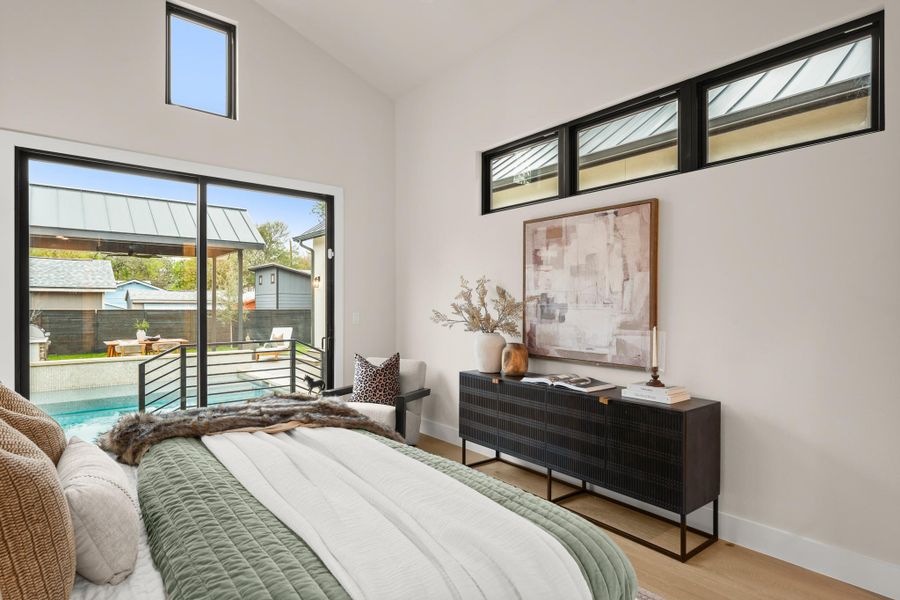 Bedroom with wood finished floors, access to exterior, and high vaulted ceiling