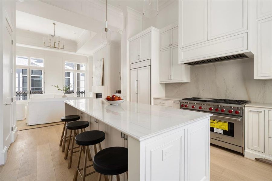 The gorgeous kitchen area features custom cabinetry custom built cabinets with inset soft close doors and drawers, designer lighting, and a marble island with seating and storage. (photo of interior model home with smaller floor plan)