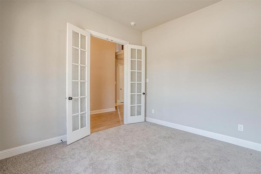 Carpeted spare room with french doors