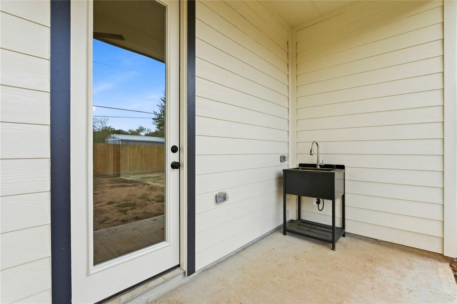 The covered patio features a convenient utility sink, ideal for washing pets, rinsing outdoor gear, or handling quick clean-ups.