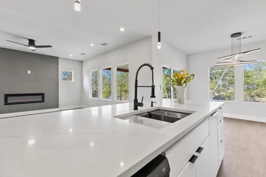 Kitchen with white cabinets, pendant lighting, light stone counters, recessed lighting, and light wood finished floors