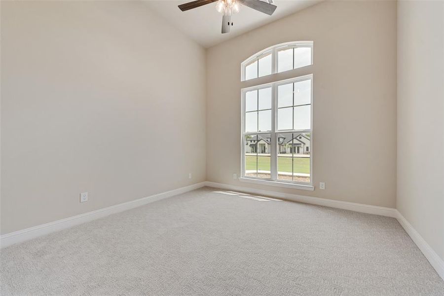 Empty room with a ceiling fan, carpet, and vaulted ceiling