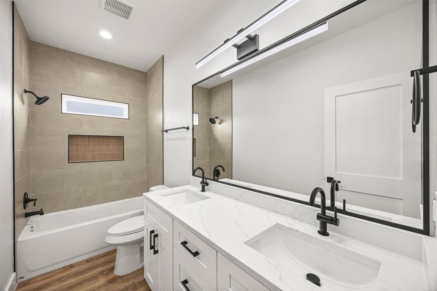 Quartz dual-sink vanity with matte black fixtures and oversized framed mirror.