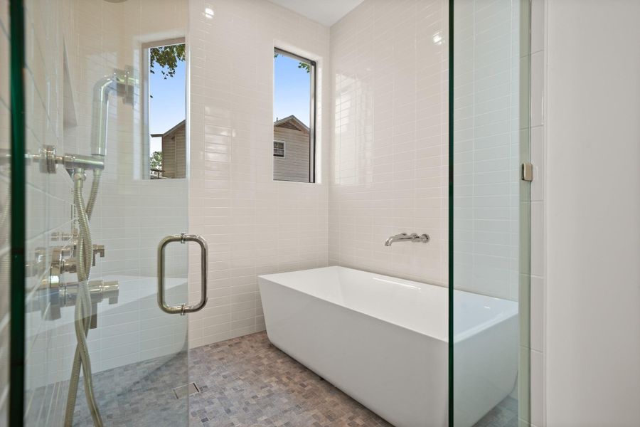 Full bathroom with tile walls, a freestanding bath, and a stall shower