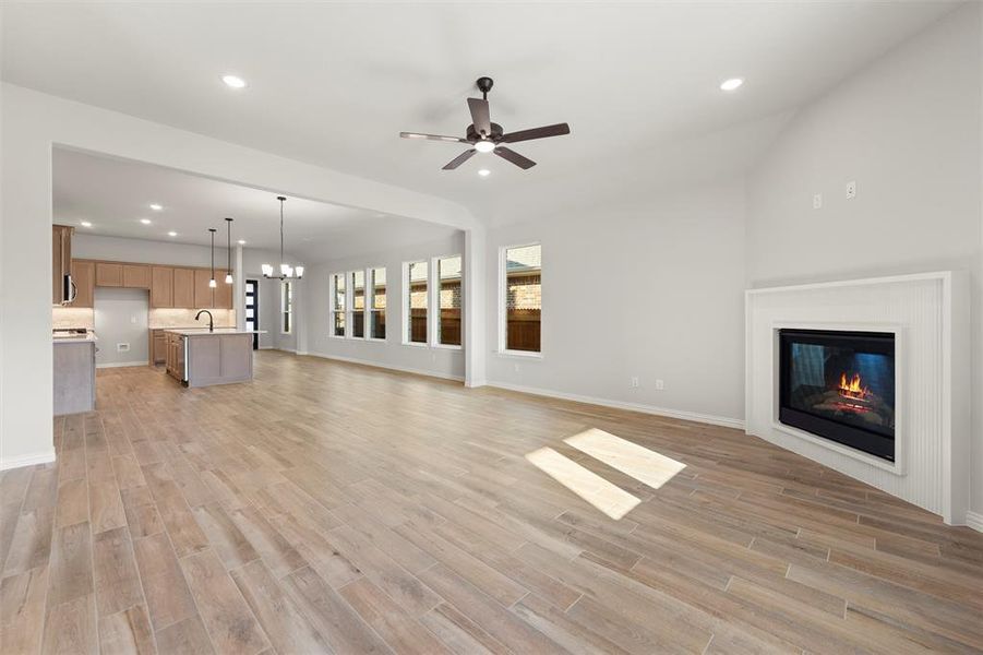 Unfurnished living room featuring recessed lighting, a chandelier, wood finish floors, a glass covered fireplace, and ceiling fan Unfurnished living room featuring recessed lighting, a chandelier, wood finish floors, a glass covered fireplace, and ceiling fan