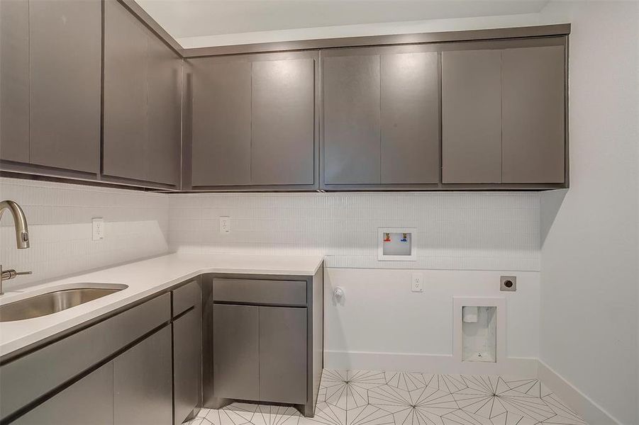 Clothes washing area featuring hookup for a washing machine, electric dryer hookup, light tile floors, sink, and cabinets