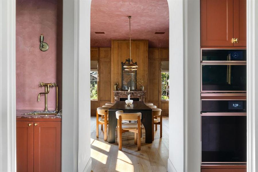 Kitchen featuring brown cabinetry, light wood finished floors, decorative light fixtures, and a textured ceiling