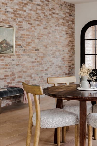 Dining area with light wood-style floors and brick wall