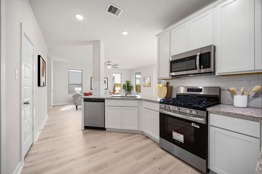 The L-shaped counter configuration maximizes usable prep space, while a corner sink area benefits from natural light provided by a window in the adjacent living space. *Virtually Staged The L-shaped counter configuration maximizes usable prep space, while a corner sink area benefits from natural light provided by a window in the adjacent living space. *Virtually Staged