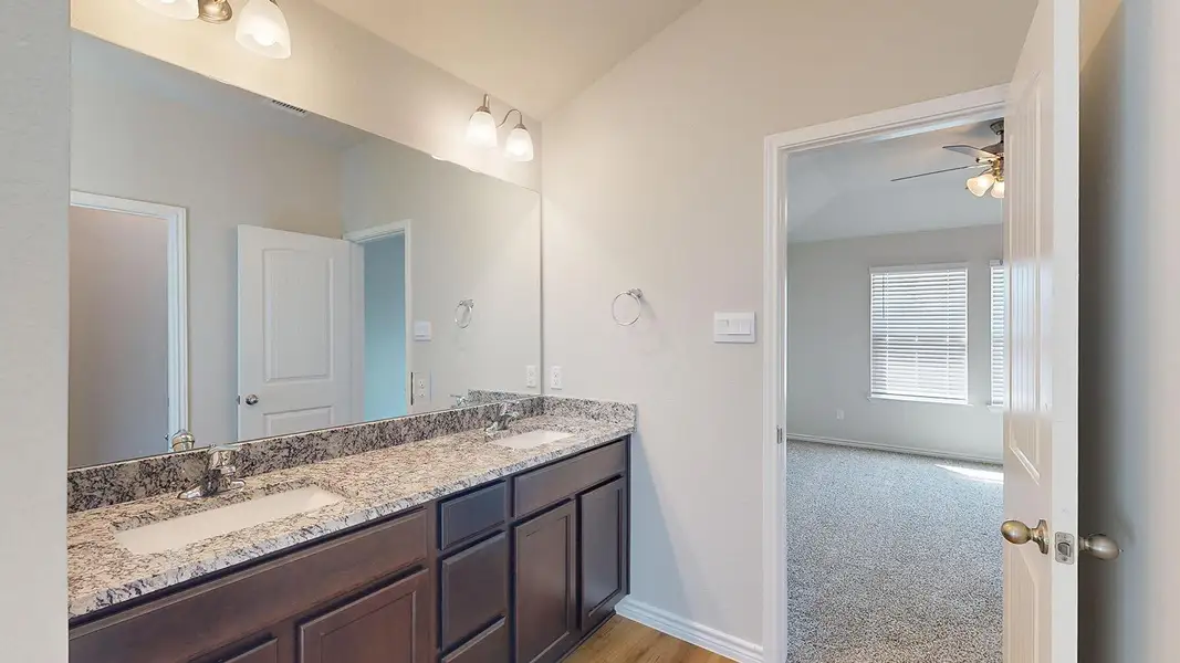 Bathroom with double vanity, ceiling fan, light carpet, and vaulted ceiling