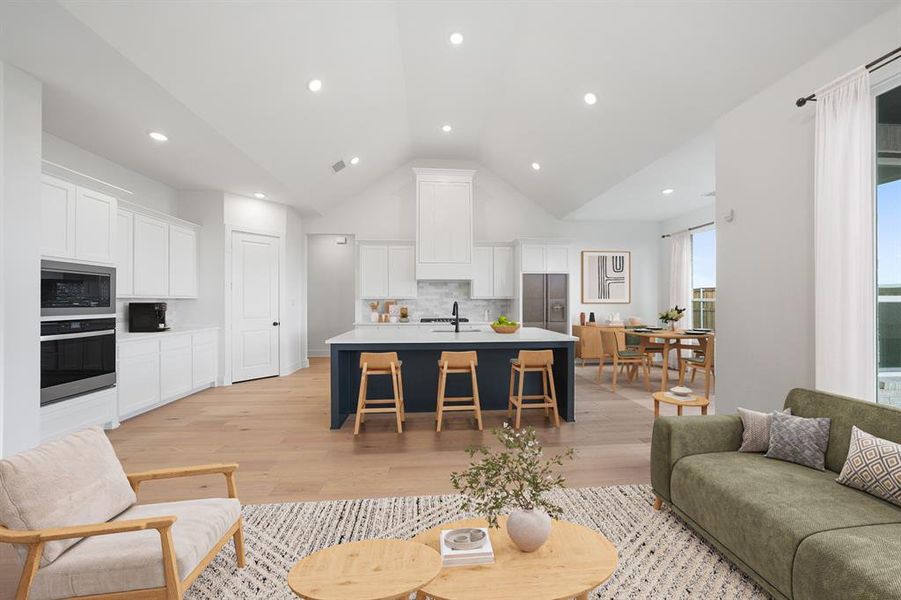 Living room with vaulted ceiling, light wood finished floors, and recessed lighting