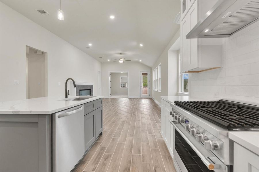 An open concept design seamlessly connects the culinary space to a living area featuring a sleek fireplace.