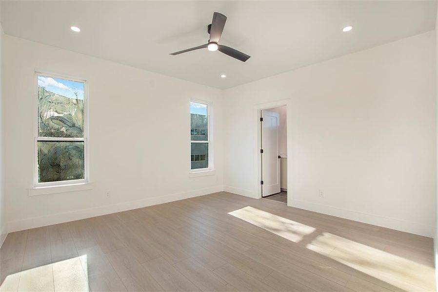 Empty room with ceiling fan and light hardwood / wood-style floors