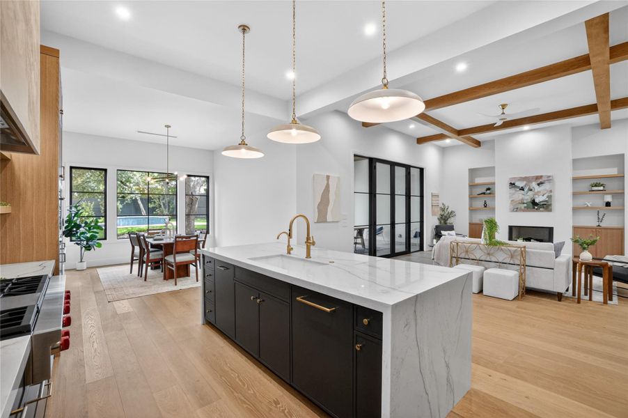A grand kitchen island with a waterfall edge anchors an open-concept living space, featuring a fireplace and large windows.