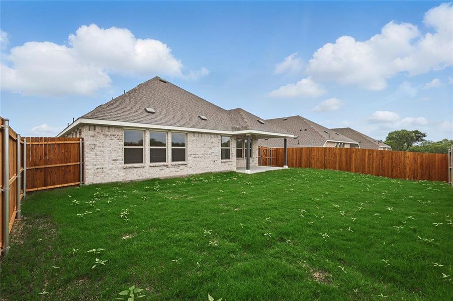 Back of house with brick siding, a fenced backyard, a lawn, and a shingled roof Back of house with brick siding, a fenced backyard, a lawn, and a shingled roof